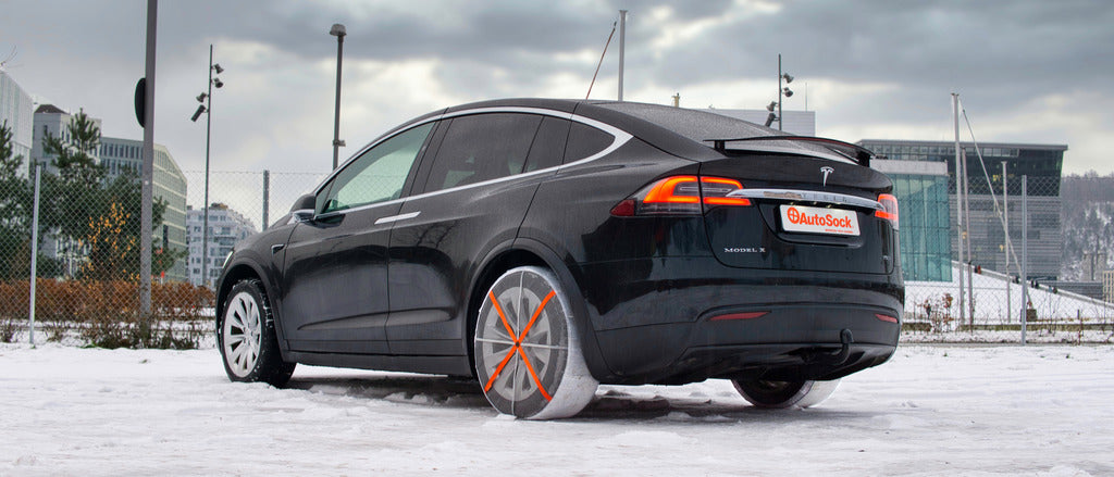 AutoSock mounted on rear wheels of an electrical car, standing on snow