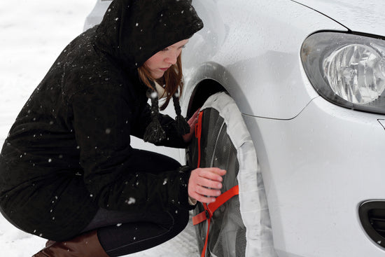Woman installs AutoSock on the front wheel of a car