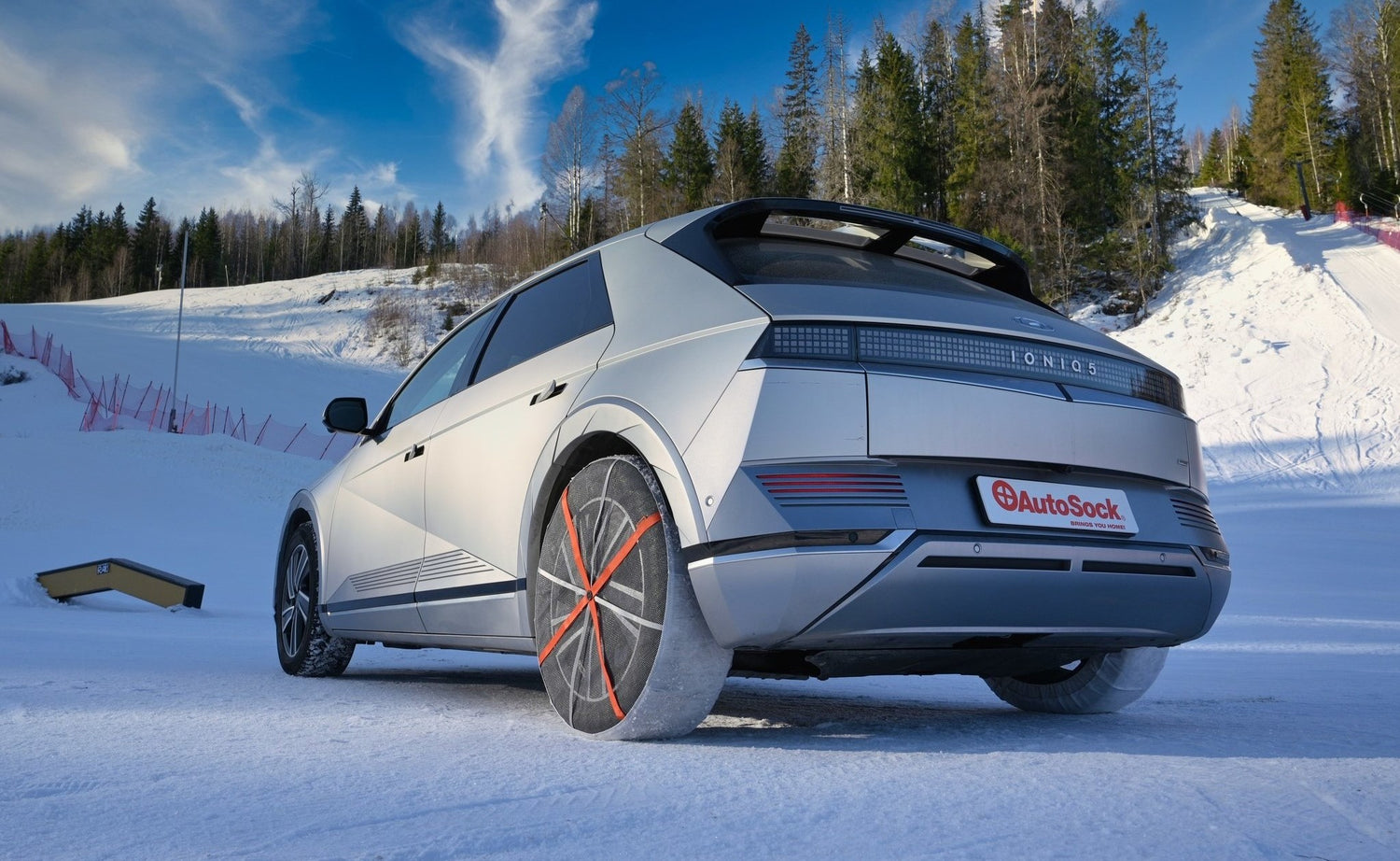 AutoSock mounted on rear wheels of a car, standing on snow in winter nature